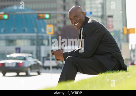 African American businessman sitting in grass Banque D'Images