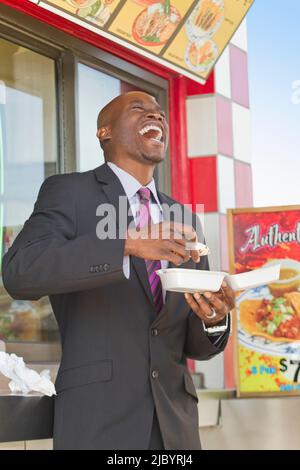 Rire African American businessman eating lunch Banque D'Images