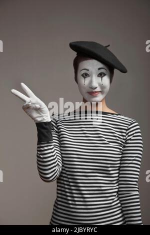 Femme en costume mime faisant signe de paix Banque D'Images