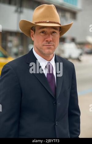 Man in cowboy hat on city street Banque D'Images