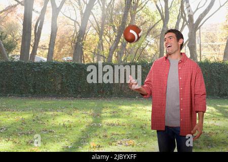 Caucasian man throwing football in backyard Banque D'Images