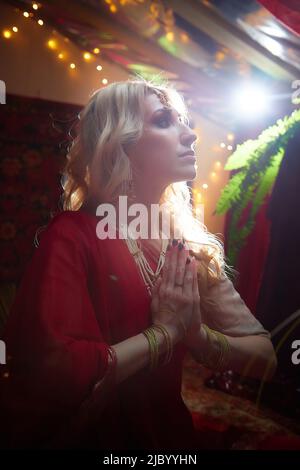 Une belle fille européenne qui ressemble à une femme arabe dans une pièce rouge dans un harem. Photo d'un style oriental odalisque. Un modèle pose dans un sari AS Banque D'Images