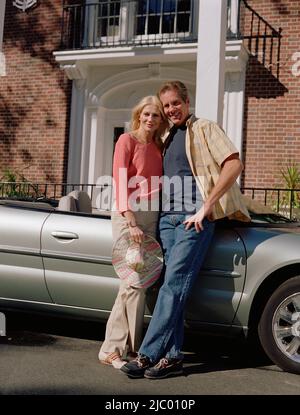 Middle-aged couple leaning on convertible Banque D'Images