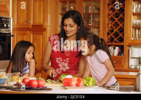 La mère et les filles indiennes preparing food in kitchen Banque D'Images