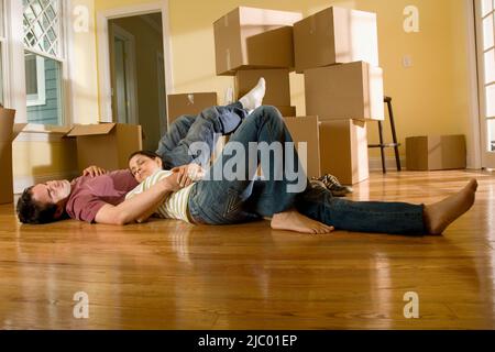 Couple sur le plancher à côté de boîtes de déménagement Banque D'Images