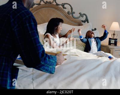 African American father apportant le petit déjeuner au lit à sa mère et fils Banque D'Images