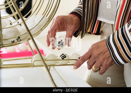 Femme âgée de ramasser une boule de bingo Banque D'Images
