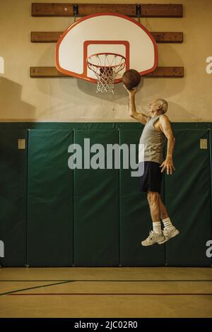 De vieux hommes sautant à slam dunk un terrain de basket-ball Banque D'Images