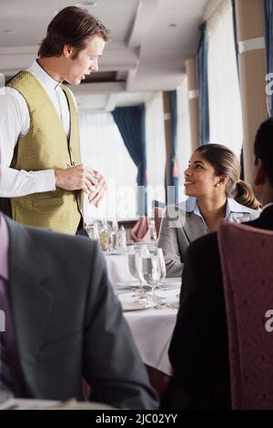 Un garçon prenant l'ordre d'une femme d'affaires dans un restaurant Banque D'Images