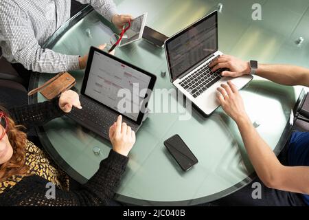 Vue aérienne de trois personnes travaillant sur des ordinateurs et des tablettes. Banque D'Images