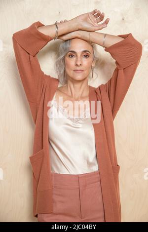 Jeune femme d'âge moyen avec ses mains au-dessus de sa tête regarde dans l'appareil photo. Banque D'Images