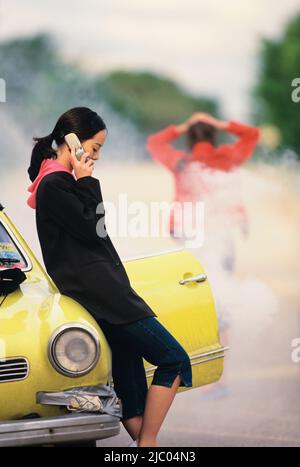 Woman talking on cell phone sur panne de voiture Banque D'Images