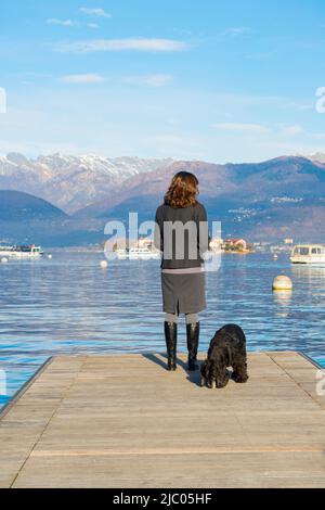 Femme élégante debout sur un quai avec son chien à Stresa, Piémont, Italie. Banque D'Images