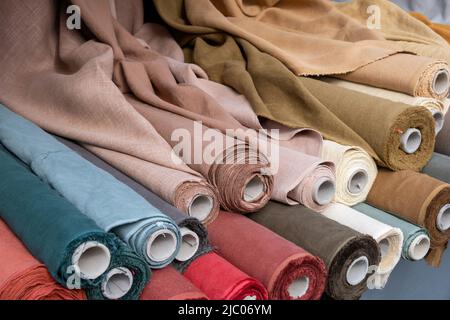 Rouleaux de tissu de fond beige et marron. Vieux rouleaux de carton avec lin coloré et toile textile sur un marché de détail, de gros plan, Banque D'Images
