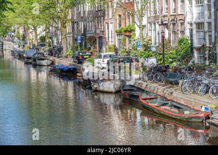 Bateaux amarrés sur l'eau du canal. Amsterdam pays-Bas. Vélos et voitures garés dans la rue, maisons traditionnelles en briques à la façade, espace de copie Banque D'Images