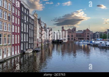 Maisons d'Amsterdam, réflexions dans l'eau du canal, ciel bleu au crépuscule. Quartier touristique Damrak, pays-Bas Hollande Banque D'Images