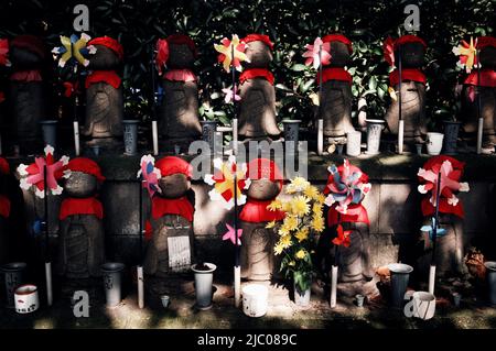 Des rangées de statues de Jizo Bosatsu décorées de casquettes et de bavoirs en tricot et de pignons pour représenter des enfants décédés dans un cimetière, Tokyo, Japon Banque D'Images