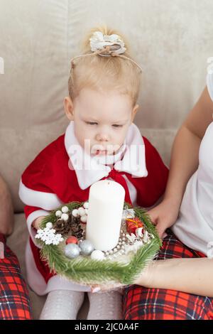 Enfant fille vêtue d'une robe de noël avec implants cochléaires s'amusant à la maison - diversité et aide auditive et technologies innovantes pour le traitement Banque D'Images