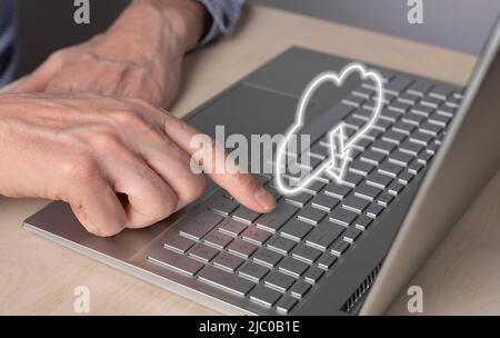 Cloud computing. Homme utilisant un ordinateur portable pour récupérer des fichiers à partir du stockage en ligne. Gros plan de l'index en appuyant sur le bouton ENTER. Photo de haute qualité Banque D'Images