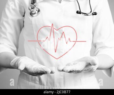 Cœur avec rythme cardiaque sur les mains du médecin en gants. Réalisation d'un test d'électrocardiogramme, vérification du concept des problèmes cardiaques. Travail du cardiologue. Noir et blanc. Photo de haute qualité Banque D'Images