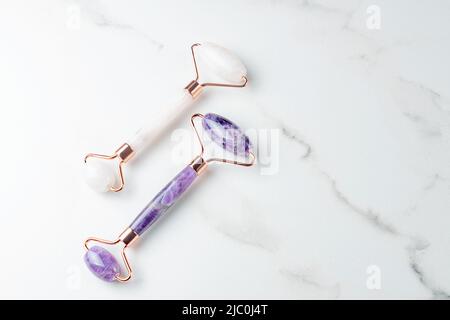 gros plan sur les rouleaux amethyst et rose quartz. Rouleaux de différentes couleurs pour le massage du visage. Vue de dessus, espace pour le texte. Concept de soins de beauté pour le visage. Cadre, Banque D'Images