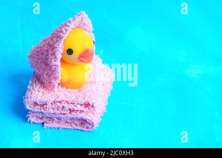 Bébé canard enveloppé dans une serviette et placé sur une pile de serviettes douces sur fond bleu avec espace pour copier. Temps de bain pour les tout-petits. Banque D'Images