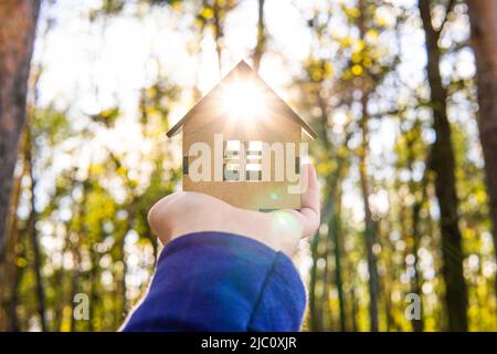 Maison miniature en bois à la main à l'extérieur. Rayons du soleil qui passent par la fenêtre. Banque D'Images