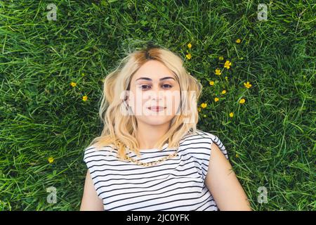 jolie fille blonde reposant sur l'herbe verte. gros plan moyen. Photo de haute qualité Banque D'Images