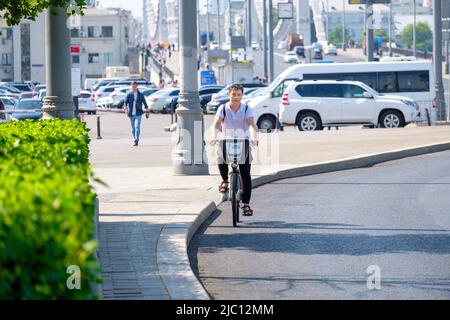 Moscou. Russie. 9 juin 2022. Un jeune homme fait un vélo loué dans la rue par une journée ensoleillée. Mise au point sélective. Vélo le long de la rue de Moscou. Banque D'Images