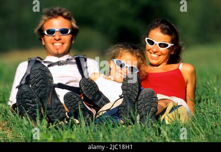 père, mère et fille allongé sur la prairie, freinant pendant une randonnée, , Banque D'Images
