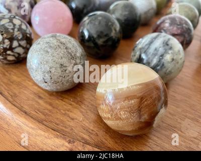 Sphère en cristal poli multicolore à jaspe barrée avec d'autres boules de pierre semi-parallèles pour la méditation, gros plan sélectif Banque D'Images