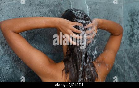 Vue arrière de la jeune femme caucasienne prenant une douche dans la salle de bains à la maison Banque D'Images