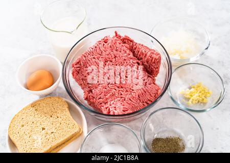 Ingrédients mesurés dans des bols à mélanger en verre pour préparer du pain de viande. Banque D'Images