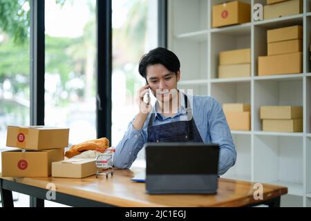 Les femmes d'affaires asiatiques de PME utilisent ordinateur portable vérifier client commande en ligne des boîtes d'expédition à la maison. Démarrage PME entrepreneur petite entreprise freelance Banque D'Images