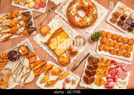 Ensemble d'assiettes avec desserts, palmiers au chocolat, croissants sucrés et salés, gâteaux éponge de diverses saveurs, en-cas salés, cupcak assorti Banque D'Images