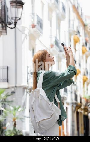 jeune voyageur avec sac à dos prendre des photos sur téléphone portable dans la rue urbaine de valence Banque D'Images