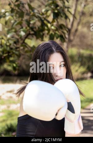 boxeur jeune femme avec gants blancs dans un parc Banque D'Images