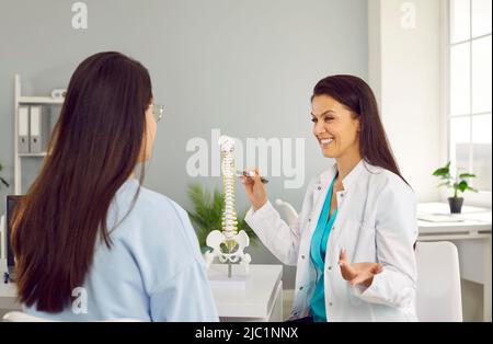 Une physiothérapeute amicale dans le bureau de l'hôpital conseille la jeune femme sur la hernie intervertébrale. Banque D'Images