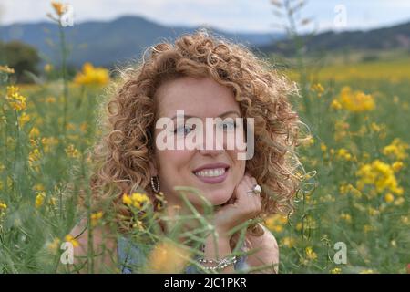 Fille aux cheveux blonds, pensant la manière et avec une main sur sa tête et l'autre tenant le bloc-notes. Banque D'Images