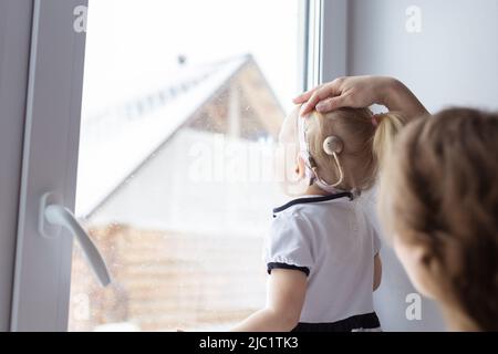Bébé avec implant cochléaire aide auditive s'amuser avec sa mère - surdité et concept de diversité. Copier l'espace et l'emplacement pour la publicité Banque D'Images