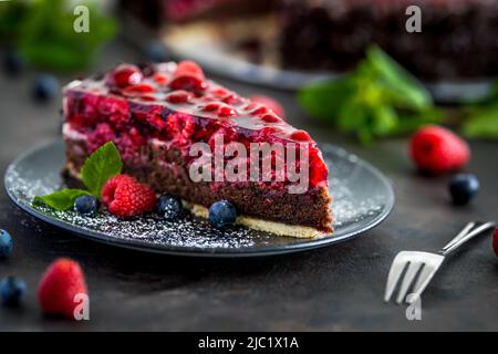 Gâteau aux framboises avec baies fraîches sur une assiette noire Banque D'Images