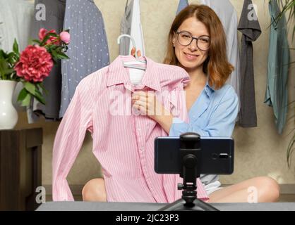 Une femme blogueuse montre des vêtements à la mode prenant des photos sur un téléphone portable. Ventes en ligne à l'aide d'un smartphone. Influenceur au travail. Banque D'Images