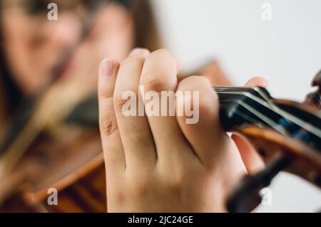 gros plan main femelle sur platine à violon faire une note, avec femme dans un arrière-plan flou avec espace de copie, se concentrer sur main. Banque D'Images