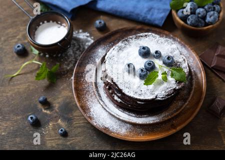 Jour de crêpes, dessert d'été. Délicieux crêpes au chocolat aux bananes américaines maison avec bleuets sur une table rustique. Banque D'Images