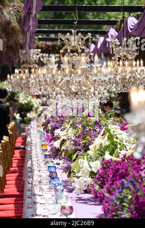 Magnifiques lustres en cristal avec des ampoules au-dessus de la table de célébration avec vaisselle pour la cérémonie. Banque D'Images