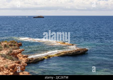 Côte rocheuse de l'île principale, surface de mer sans limite avec des ondulations légères, petite île non loin de la côte, Ibiza, Iles Baléares, Espagne Banque D'Images