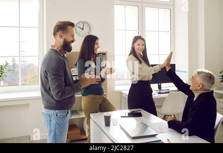 Une équipe de collègues de bureau heureux et d'amis célébrant le succès et s'amusant au travail Banque D'Images