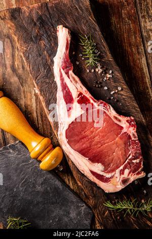 Bœuf frais tomahawk pour barbecue ou barbecue sur bois avec sel et poivre noir, brunâtre au romarin. Vue sur le dessus, Journée mondiale de la gastronomie Banque D'Images