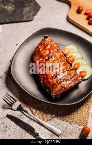 Côtes de porc grillées barbecue sur plaque noire, vue sur le dessus, Journée mondiale de la nourriture Banque D'Images