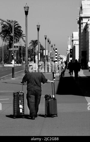 Un homme roule ses valises le long du trottoir d'Embarcadero en se promenant vers son bateau de croisière amarré à San Francisco, en Californie. Banque D'Images